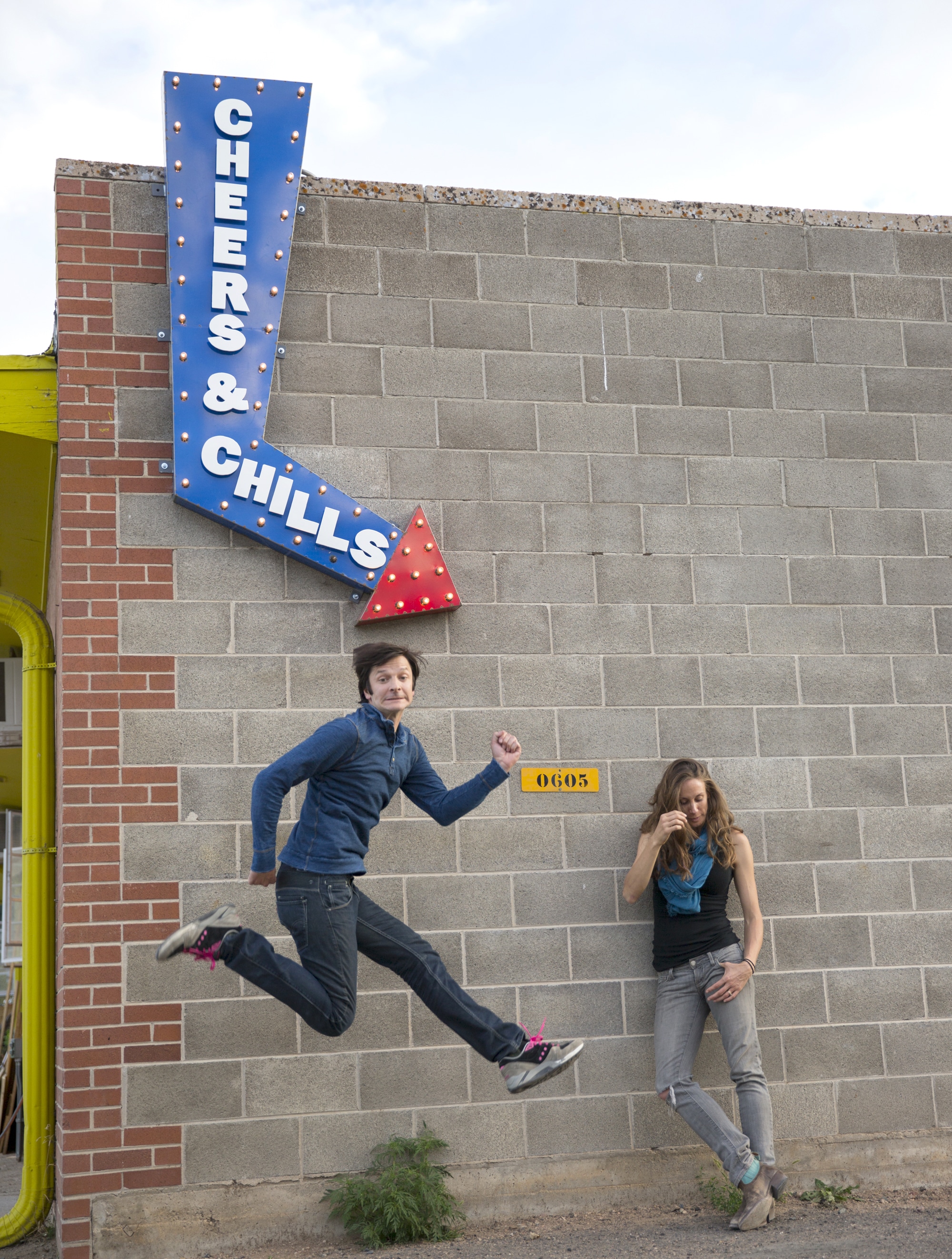 Robb Shurr and Lucia Hyde standing in from of a sign that says cheers and chills for our about page photo