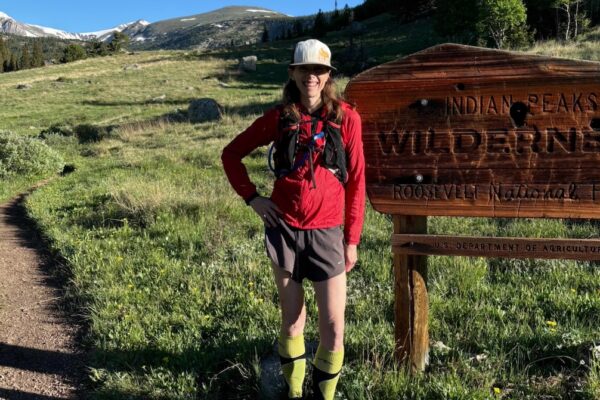 Runner in red jacket standing in front of Wilderness sign