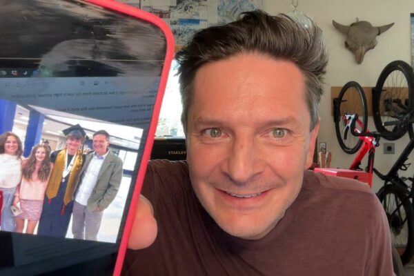 Robb holding up a phone with image of his family on son's graduation